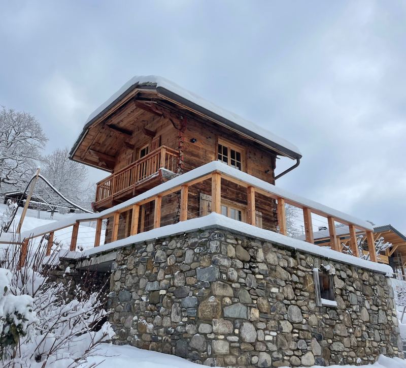 Chalet Ourson in winter: a larch mazot with a snow-covered roof and wooden balconies above a dry-stone wall